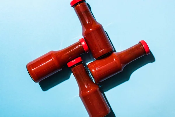 Top view of delicious ketchup in bottles on blue background — Stock Photo