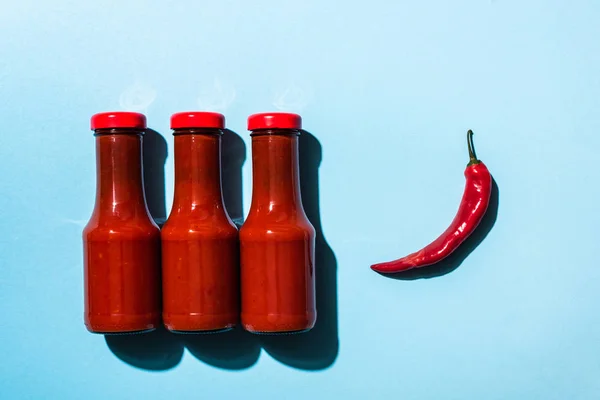 Vue du dessus de la sauce chili savoureuse avec du piment sur la surface bleue — Photo de stock