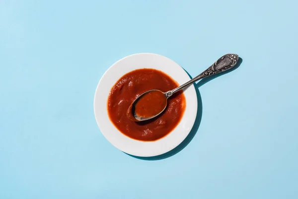 Vista superior del plato de deliciosa salsa de tomate en la superficie azul - foto de stock