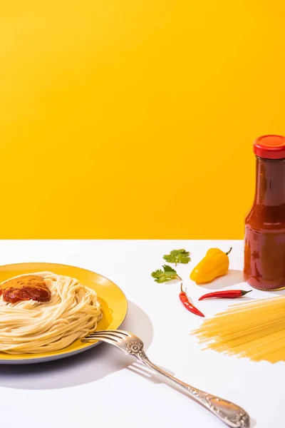 Delicious spaghetti with ketchup and peppers on white surface on yellow background — Stock Photo