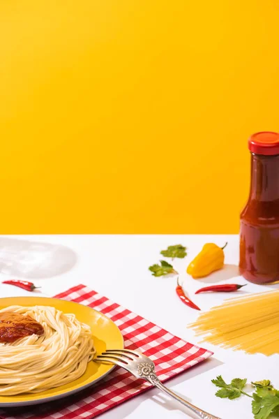 Espaguetis con salsa de tomate y papeles sobre superficie blanca sobre fondo amarillo - foto de stock