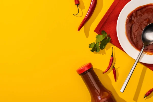 Vue du dessus de la sauce tomate avec piments forts et coriandre sur fond jaune — Photo de stock