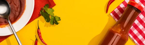 Top view of homemade ketchup with chili peppers and cilantro on yellow background, panoramic shot — Stock Photo