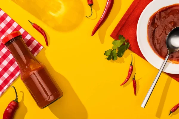 Vista superior de la sabrosa salsa de chile con chiles y cilantro sobre fondo amarillo - foto de stock