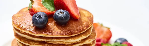 Close up view of delicious pancakes with honey, blueberries and strawberries, panoramic shot — Stock Photo