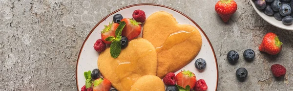 Top view of heart shaped pancakes with berries on grey concrete surface, panoramic shot — Stock Photo