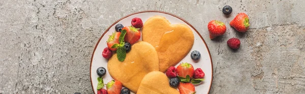 Top view of heart shaped pancakes with berries on grey concrete surface, panoramic shot — Stock Photo