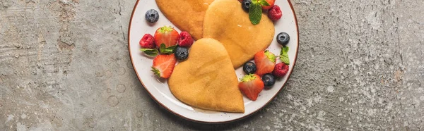 Top view of heart shaped pancakes with berries on grey concrete surface, panoramic shot — Stock Photo