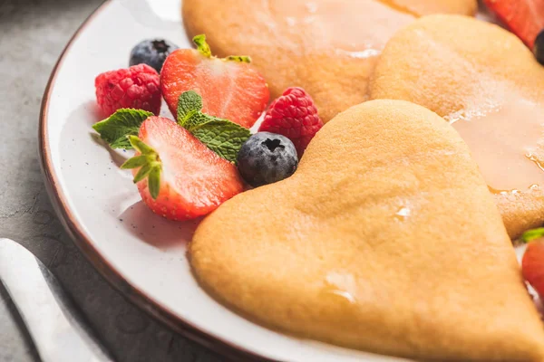Nahaufnahme von leckeren herzförmigen Pfannkuchen mit Beeren auf dem Teller — Stockfoto