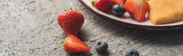 Close up view of fresh berries near delicious heart shaped pancakes on grey concrete surface, panoramic shot — Stock Photo