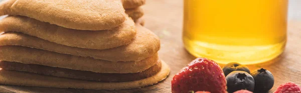 Deliciosos panqueques en forma de corazón con bayas en tablero de madera con miel, tiro panorámico - foto de stock