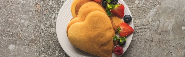 Top view of heart shaped pancakes with berries on grey concrete surface, panoramic shot — Stock Photo