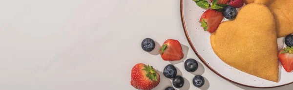 Top view of tasty heart shaped pancakes with berries and mint on white background, panoramic shot — Stock Photo