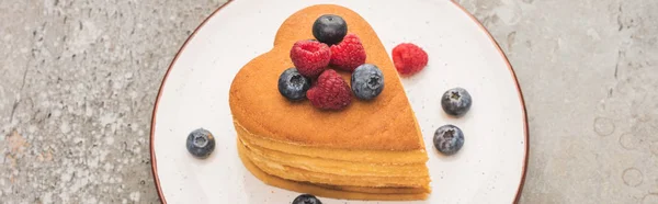 Heart shaped pancakes with berries on plate on grey concrete surface, panoramic shot — Stock Photo