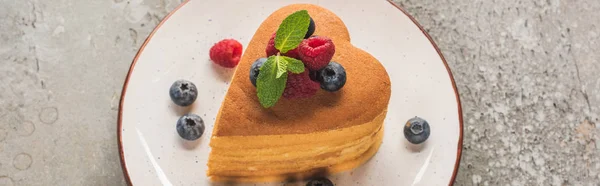 Crêpes en forme de coeur avec des baies et de la menthe sur plaque sur la surface en béton gris, vue panoramique — Photo de stock