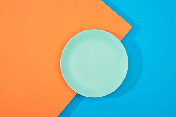 Top view of empty plate on colorful blue and orange surface — Stock Photo