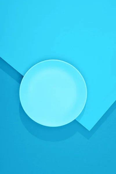 Top view of empty plate on colorful blue surface — Stock Photo