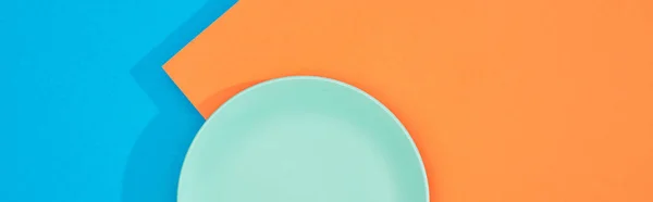 Vista superior de la placa vacía en la superficie de color azul y naranja, plano panorámico - foto de stock