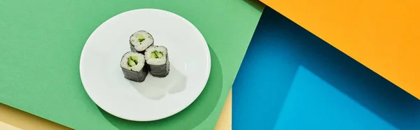 Fresh maki with cucumber on plate on multicolored surface, panoramic shot — Stock Photo