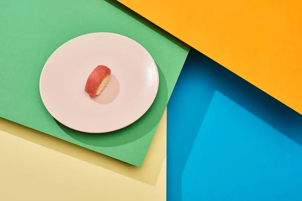 Свежий нигири с тунцом на тарелке на разноцветной поверхности — стоковое фото