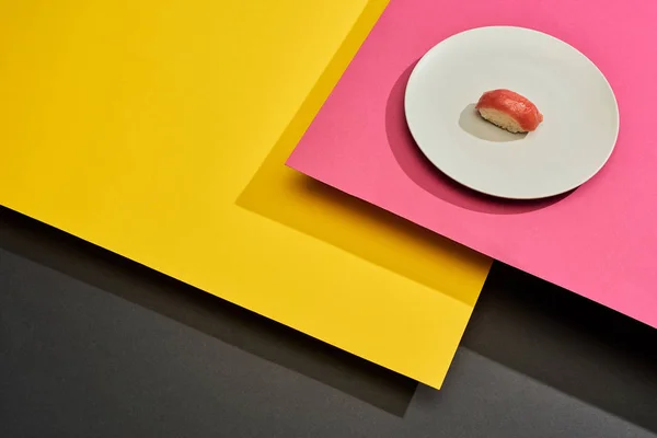 Fresh nigiri with tuna on plate on black, pink, yellow surface — Stock Photo