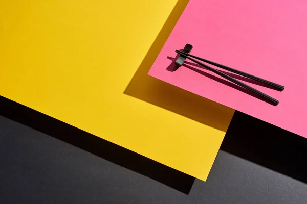 Chopsticks on pink, yellow and black surface — Stock Photo