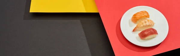 Свежий нигири с лосося, креветок и тунца на красной, желтой и черной поверхности, панорамный снимок — стоковое фото