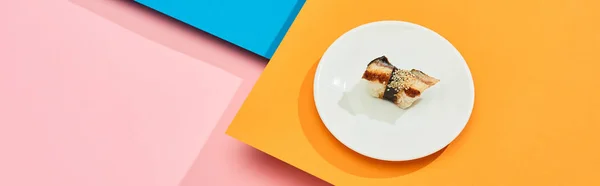 Fresh nigiri with eel on plate on blue, pink, orange surface, panoramic shot — Stock Photo