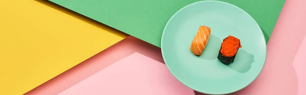 Fresh nigiri with salmon and red caviar on yellow, pink, green background, panoramic shot — Stock Photo