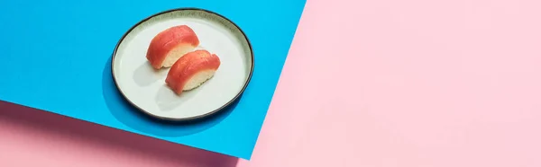 Top view of fresh nigiri with tuna on blue, pink background, panoramic shot — Stock Photo