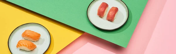 Fresh nigiri with salmon and tuna on yellow, pink, green background, panoramic shot — Stock Photo