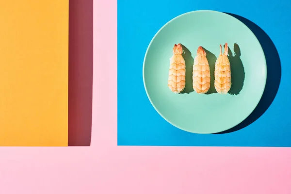 Draufsicht auf frische Nigiri mit Garnelen auf blauem, rosa, orangefarbenem Hintergrund — Stockfoto