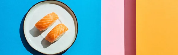 Top view of fresh nigiri with salmon on blue, pink, orange background, panoramic shot — Stock Photo