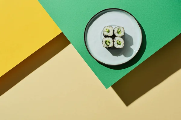 Top view of fresh nigiri with cucumber on green and yellow surface — Stock Photo