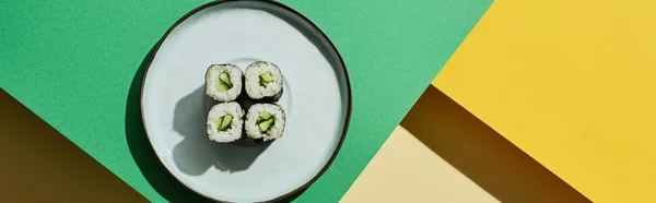 Vista superior de nigiri fresco com pepino na superfície verde e amarela, tiro panorâmico — Fotografia de Stock