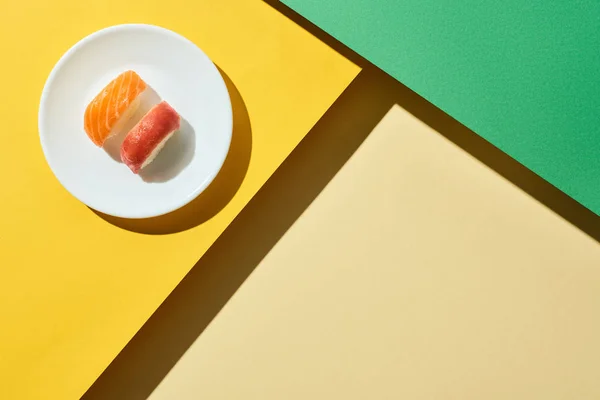 Vista dall'alto di nigiri freschi con salmone e tonno su superficie verde e gialla — Foto stock