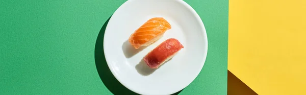 Top view of fresh nigiri with salmon and tuna on green and yellow surface, panoramic shot — Stock Photo