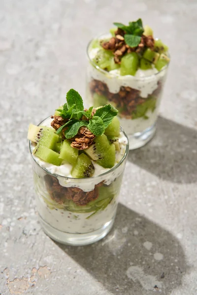 Selective focus of fresh granola with kiwi and yogurt on grey concrete surface — Stock Photo