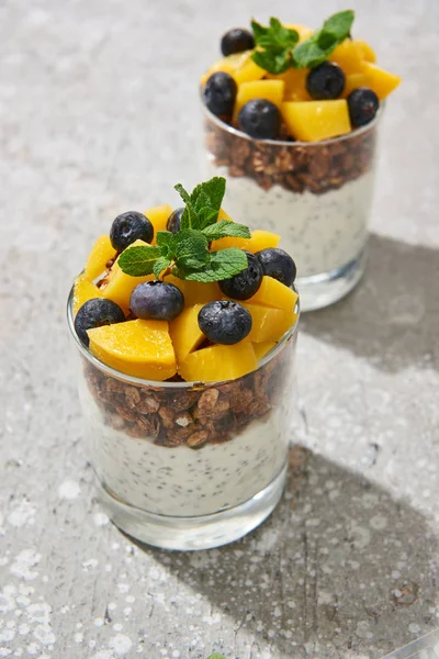 Selective focus of fresh granola with canned peach, blueberries and chia seeds on grey concrete surface — Stock Photo