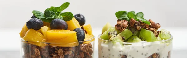 Close up view of fresh granola with kiwi and canned peach with blueberries isolated on white, panoramic shot — Stock Photo