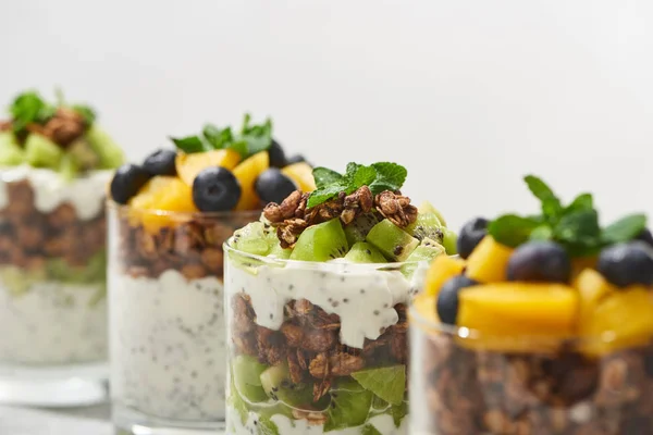 Selective focus of fresh granola with kiwi and canned peach with blueberries isolated on white — Stock Photo