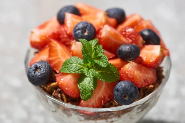 Close up view of delicious granola with berries and mint on grey concrete surface — Stock Photo