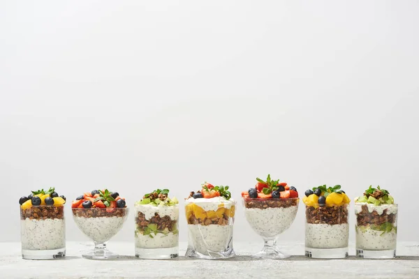 Deliziosa muesli in bicchieri con frutta e bacche isolate su bianco — Foto stock