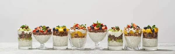 Delicious granola in glasses with fruits and berries isolated on white, panoramic shot — Stock Photo