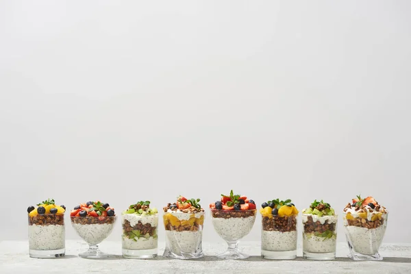 Délicieux granola dans des verres avec des fruits et des baies isolés sur blanc — Photo de stock