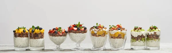 Délicieux granola dans des verres avec des fruits et des baies isolés sur blanc, vue panoramique — Photo de stock