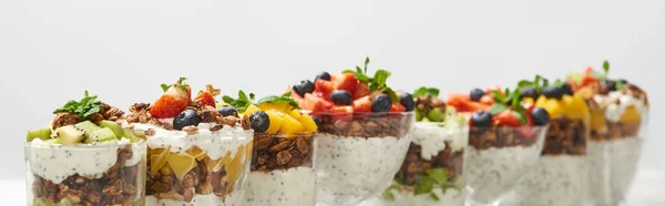 Foco seletivo de granola deliciosa em copos com frutas e bagas isoladas em branco, tiro panorâmico — Fotografia de Stock