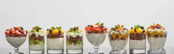 Délicieux granola dans des verres avec des fruits et des baies isolés sur blanc, vue panoramique — Photo de stock