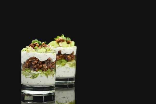 Селективный фокус свежей мюсли с киви и йогуртом, выделенных на черном — стоковое фото