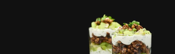 Селективный фокус свежей гранолы с киви и йогуртом, выделенный на черном, панорамный снимок — стоковое фото